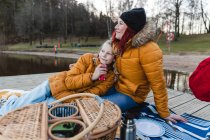 Любимая семья с дочкой-подростком отдыхает на деревянной набережной и наслаждается пикником в осеннем лесу — стоковое фото