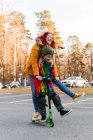 Восхищенные мать и дочь катаются на скутере на парковке, развлекаясь по выходным осенью — стоковое фото
