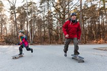 Безтурботний батько і дочка в шоломах катаються на скейтбордах в парку і розважаються разом у вихідні — стокове фото