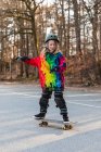 Энергичная девочка-подросток в защитном снаряжении, катается на скейтборде — стоковое фото