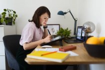 Vista laterale della donna disegno immagine su tavoletta grafica mentre seduto a tavola in ufficio a casa — Foto stock