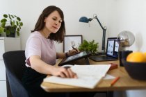 Вид збоку жінки малює зображення на графічному планшеті, сидячи за столом в домашньому офісі — стокове фото