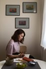 Dessin de graphiste féminin concentré dans le carnet de croquis tout en travaillant à distance sur le projet à table avec une tasse de café à la maison — Photo de stock