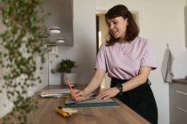 Зміст ескізу жіночого графічного дизайнера на папері, стоячи за столом вдома і працюючи віддалено — стокове фото
