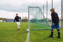 Teenager in Sportbekleidung spielen im Sommer gemeinsam Fußball auf der grünen Wiese — Stockfoto