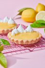 Високий кут смачних лимонних пирогів зі збитими вершками, поданими на рожевому фоні зі свіжими цитрусами — стокове фото