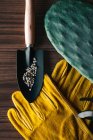 Top view of colorful gardening gloves on wooden table with small shovel of tiny gravel in daylight — Stock Photo