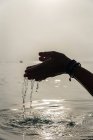 Безликая самка с горсткой воды в мокрых руках в море утром в Алькудии — стоковое фото