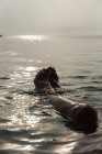 Crop barefoot legs of unrecognizable female lying in sea water and enjoying sunny morning during vacation on Playa de Muro — Stock Photo