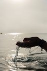 Cortar hembra sin rostro con un puñado de agua en manos mojadas en el mar por la mañana en Alcudia - foto de stock