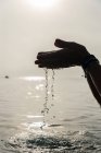 Cultiver femelle sans visage avec une poignée d'eau dans les mains humides dans la mer le matin à Alcudia — Photo de stock