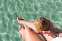 Von oben sieht man unkenntlich gewordene Frauen, die mit Kokosnusscocktail mit Stroh in der Nähe des blau plätschernden Meeres sitzen und den Sommerurlaub an der Playa de Muro genießen — Stockfoto