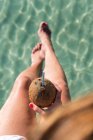 Von oben sieht man unkenntlich gewordene Frauen, die mit Kokosnusscocktail mit Stroh in der Nähe des blau plätschernden Meeres sitzen und den Sommerurlaub an der Playa de Muro genießen — Stockfoto