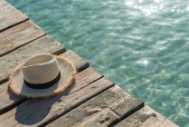 Високий кут солом'яного сонцезахисного крему розміщений на дерев'яних набережній біля блакитного моря в сонячний день влітку на Плей-де-Муро. — стокове фото