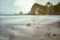 Espectacular paisaje con olas de mar espumosas lavando formaciones rocosas rugosas de diversas formas en la playa salvaje de Geirua en Asturias España - foto de stock