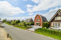 Carretera de asfalto contra edificios de viviendas exteriores y prados con árboles bajo el cielo nublado en Utrecht Países Bajos - foto de stock