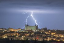 Paesaggio urbano con invecchiato famoso castello Alcazar di Toledo collocato in Spagna sotto il cielo nuvoloso di notte durante il temporale — Foto stock