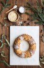 Overhead view of tasty three kings cake decorated with almond petals and coconut flakes among Eucalyptus and fir sprigs — Stock Photo