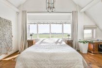 Bettdecke unter Vintage-Lampe hängt an sonnigem Tag gegen Fenster im modernen Schlafzimmer — Stockfoto