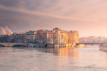 Історичні житлові будівлі, розташовані на березі річки, що тече в Парижі взимку ввечері. — стокове фото