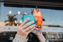 Anonyme fröhliche weibliche Teenager interagieren, während sie am Tisch in der städtischen Cafeteria Gläser mit köstlichen Erfrischungsgetränken klappern — Stockfoto