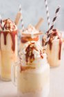 Copos variados com milkshake de caramelo doce com sorvete de baunilha e biscoitos wafer servidos na mesa — Fotografia de Stock
