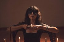 Verträumte Zauberin mit gemaltem Gesicht und Totenkopf verzaubert bei mystischem Ritual im Raum mit schwachem Licht — Stockfoto