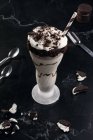 From above of tasty milkshake with crushed biscuits and straw in glass with chocolate sauce — Stock Photo