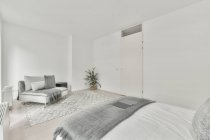 Интерьер просторной светлой спальни с удобной кроватью в современной квартире в дневное время — стоковое фото
