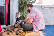 Ground level of cheerful bearded dad in checkered shirt with boy working with wooden blocks — Stock Photo