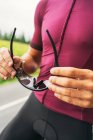 Crop atleta masculino anônimo em sportswear com óculos protetores se preparando para o treinamento na estrada durante o dia — Fotografia de Stock