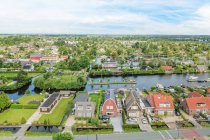 Drone view of residential building facades between river and lawns with trees under cloudy sky in Province of Utrecht Netherlands — Stock Photo