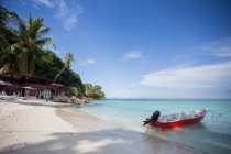 Barco no mar azul claro rolando na praia de areia molhada na Malásia — Fotografia de Stock