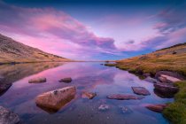 Paisagem pitoresca de rio calmo com rochas colocadas em terras altas na Serra de Guadarrama, na Espanha, sob céu colorido ao nascer do sol — Fotografia de Stock