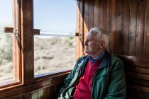Homme attrayant et vieil homme voyageant dans une vieille voiture de train en bois regardant par la fenêtre — Photo de stock