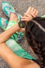 De cima de colheita anônimo feminino corredor verificando pulso na pulseira de fitness wearable moderna durante o treino na cidade — Fotografia de Stock