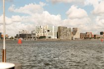 Edifícios contemporâneos de vários estágios localizados na costa do mar ondulante contra o céu nublado em Amsterdã — Fotografia de Stock