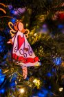 Décorations en forme d'ange et d'étoile suspendues sur des branches de sapin de Noël artificiel luisant la nuit — Photo de stock