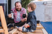 Aufrichtiges Kind mit Kalebassen-Kürbis von infundiertem Getränk gegen fröhlichen bärtigen Papa mit Thermoskanne auf verschwommenem Hintergrund — Stockfoto