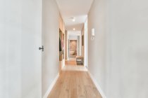 Порожній довгий коридор з білими стінами і паркетом в сучасній квартирі вдень — стокове фото