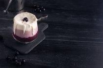 Copo de deliciosa banana e smoothie de mirtilo com chantilly na tábua de cortar contra jarro de iogurte e balde de metal — Fotografia de Stock