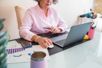 Урожай старший женщина-предприниматель с планшетом и нетбук работает за столом с графикой на бумажных листах — стоковое фото