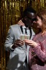 Crop sincère jeune femme embrassant élégant petit ami noir tout en tenant des verres de champagne pendant la célébration du Nouvel An — Photo de stock