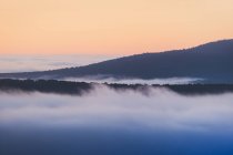 Scenic view of Pedriza with mist diffusing between Guadarrama mountain range and boulders with coniferous trees at sunrise in Spain — Stock Photo
