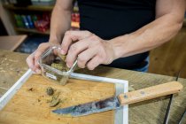 Врожай невизначений чоловік з різанням ножа сушений шматок рослини канабісу на дерев'яній дошці в робочому просторі — стокове фото