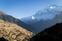 High steep slopes of mountains covered with snow located in Himalayas valley range under colorful sky in Nepal — Stock Photo