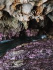 Прозрачная прозрачная волнистая морская вода, текущая через скалистую грубую пещеру с острыми неровными уступчиками — стоковое фото
