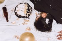 De cima do homem bêbado dormindo perto de bolo de aniversário esmagado e garrafa vazia durante a festa — Fotografia de Stock