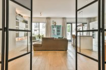 Durch Glas Tür auf Sofas in geräumigem Raum mit moderner Küche mit Essecke und Gitarre — Stockfoto