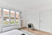 Bequemes Bett mit weißer Decke bedeckt auf Teppich in der Nähe des Fensters im stilvollen Schlafzimmer platziert — Stockfoto